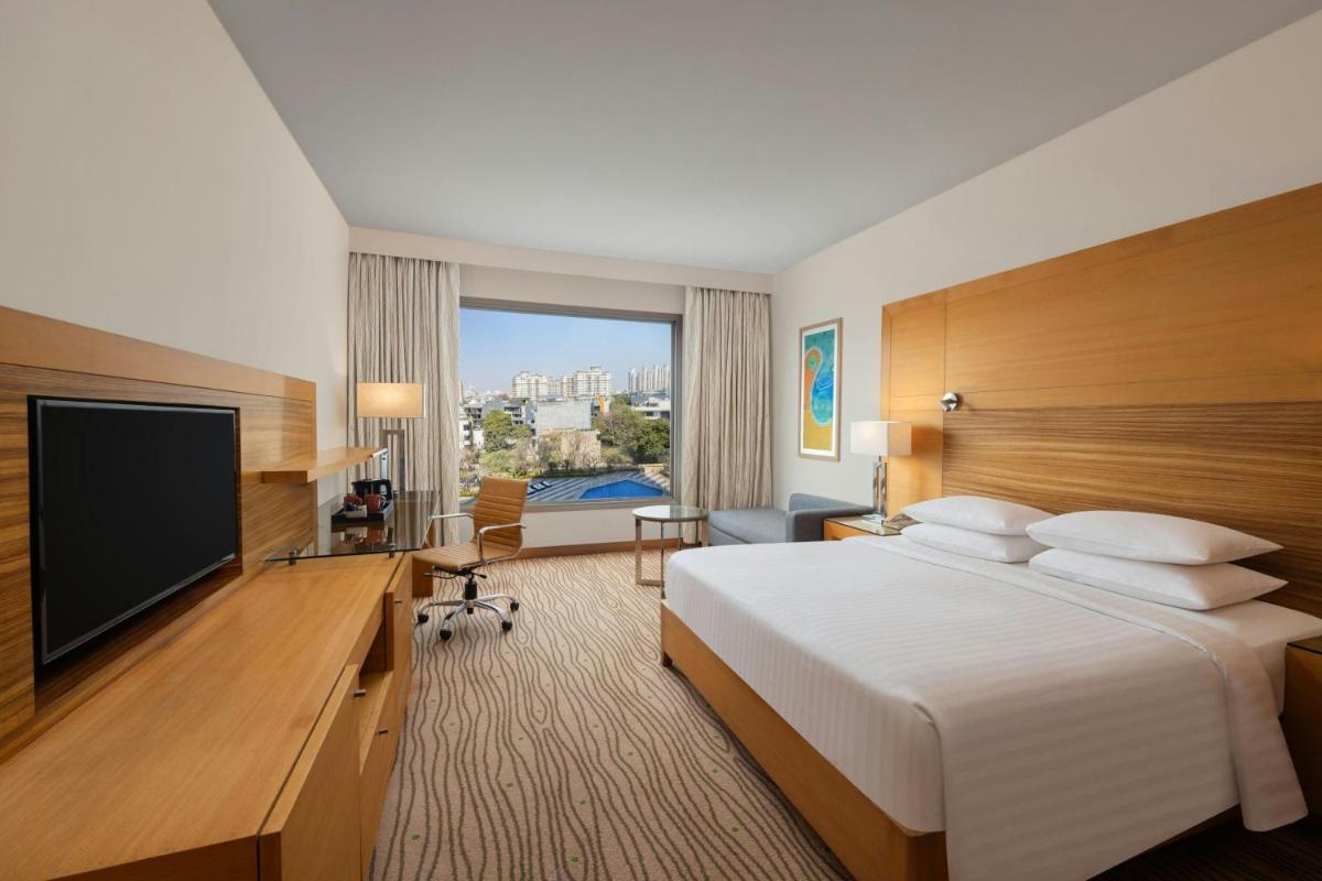 a hotel room with a bed and a flat screen tv at Courtyard by Marriott Gurugram Downtown in Gurgaon