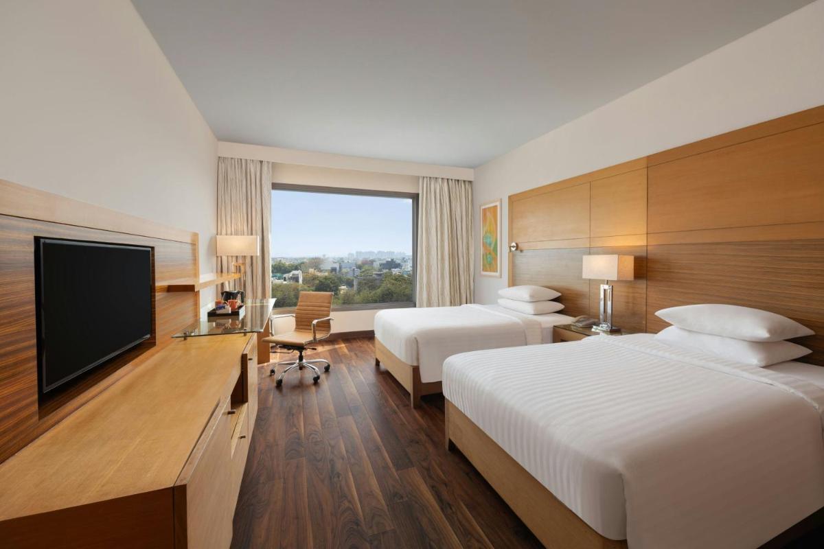 a hotel room with two beds and a flat screen tv at Courtyard by Marriott Gurugram Downtown in Gurgaon