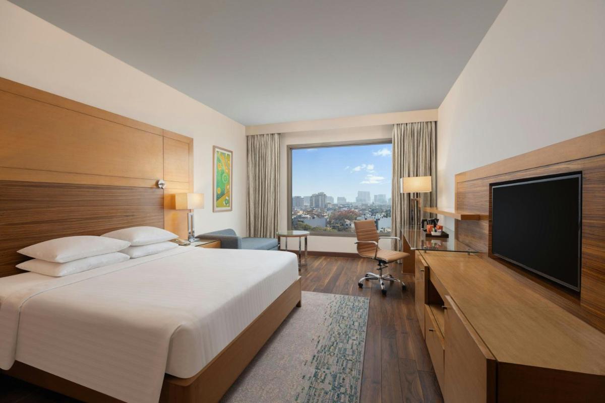 a hotel room with a bed and a flat screen tv at Courtyard by Marriott Gurugram Downtown in Gurgaon