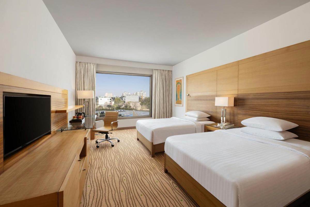 a hotel room with two beds and a flat screen tv at Courtyard by Marriott Gurugram Downtown in Gurgaon +254 photos