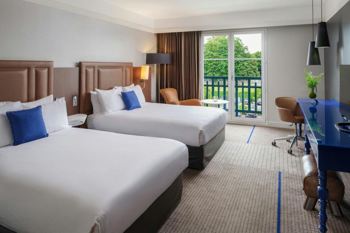 une chambre d'hôtel avec deux lits et un bureau dans l'établissement Renaissance Paris Hippodrome de St. Cloud Hotel, à Rueil-Malmaison