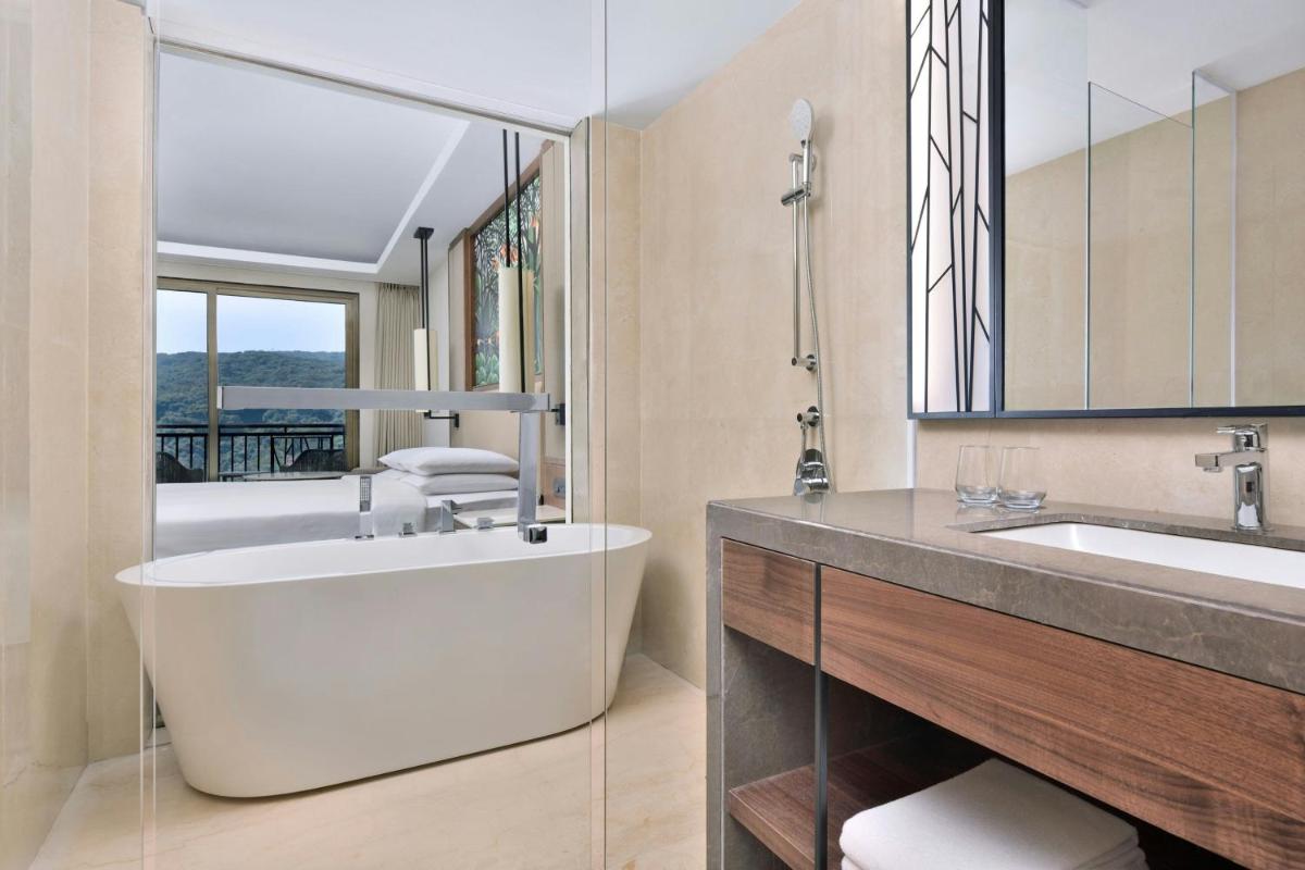 a bathroom with a tub and a sink and a mirror at Courtyard by Marriott Mahabaleshwar in Mahabaleshwar
