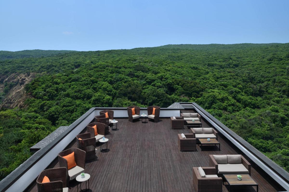 a deck with chairs and tables on top of a mountain at Courtyard by Marriott Mahabaleshwar in Mahabaleshwar