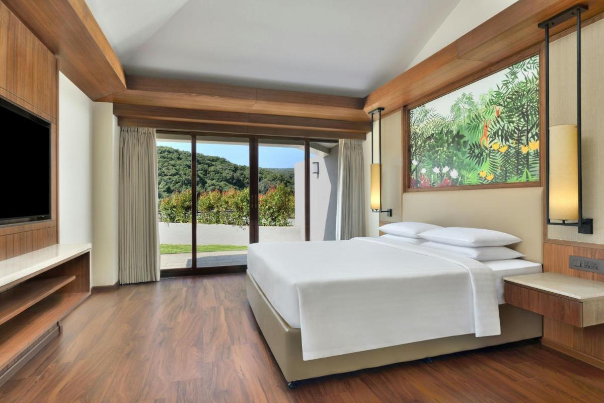 a bedroom with a white bed and a large window at Courtyard by Marriott Mahabaleshwar in Mahabaleshwar
