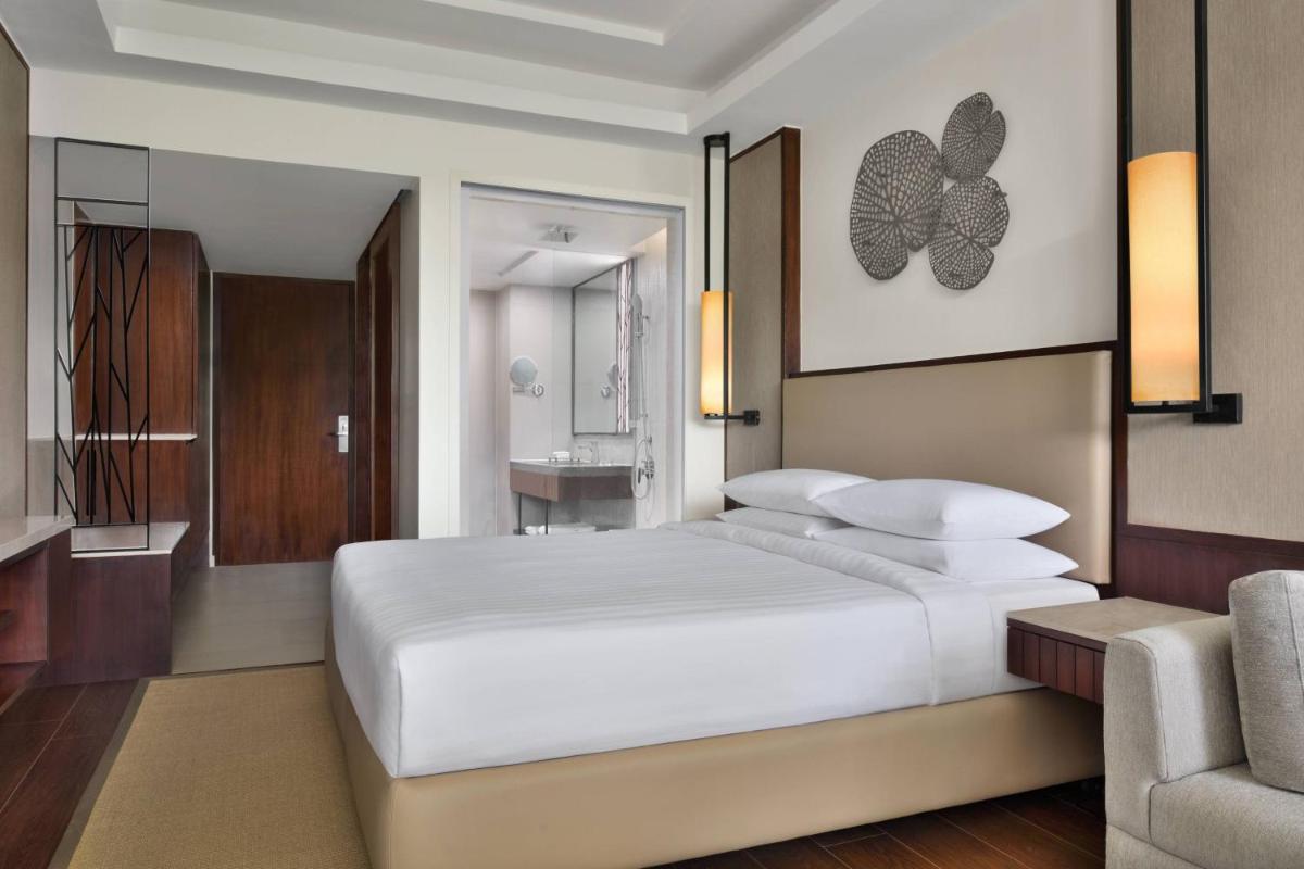 a bedroom with a large white bed and a chair at Courtyard by Marriott Mahabaleshwar in Mahabaleshwar