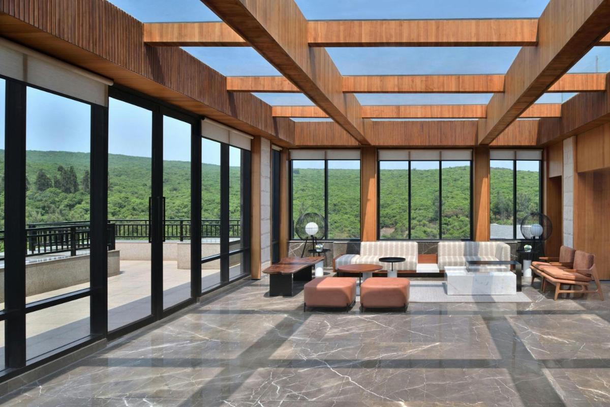a large living room with large windows and a couch at Courtyard by Marriott Mahabaleshwar in Mahabaleshwar