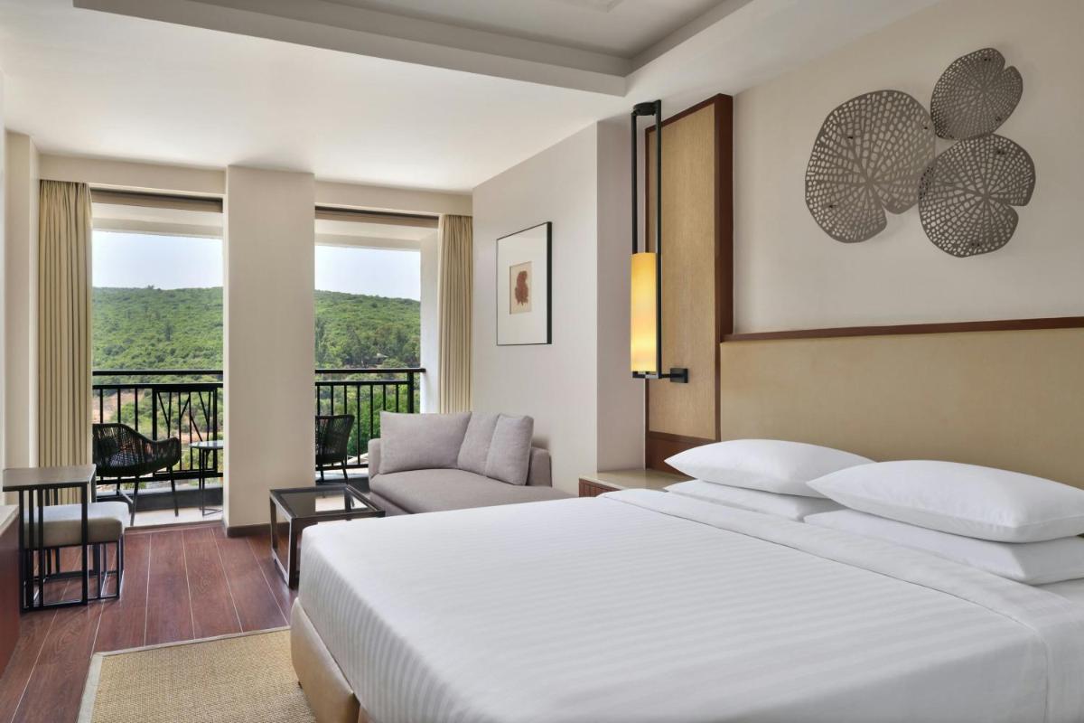 a hotel room with a bed and a balcony at Courtyard by Marriott Mahabaleshwar in Mahabaleshwar