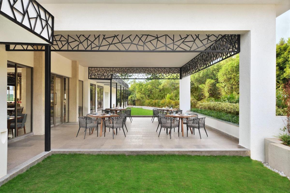 an outdoor patio with tables and chairs and grass at Courtyard by Marriott Mahabaleshwar in Mahabaleshwar