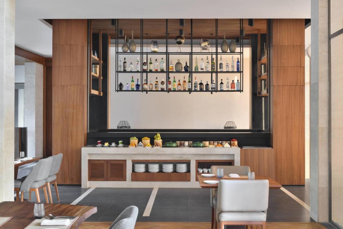a dining room with a bar with a table and chairs at Courtyard by Marriott Mahabaleshwar in Mahabaleshwar