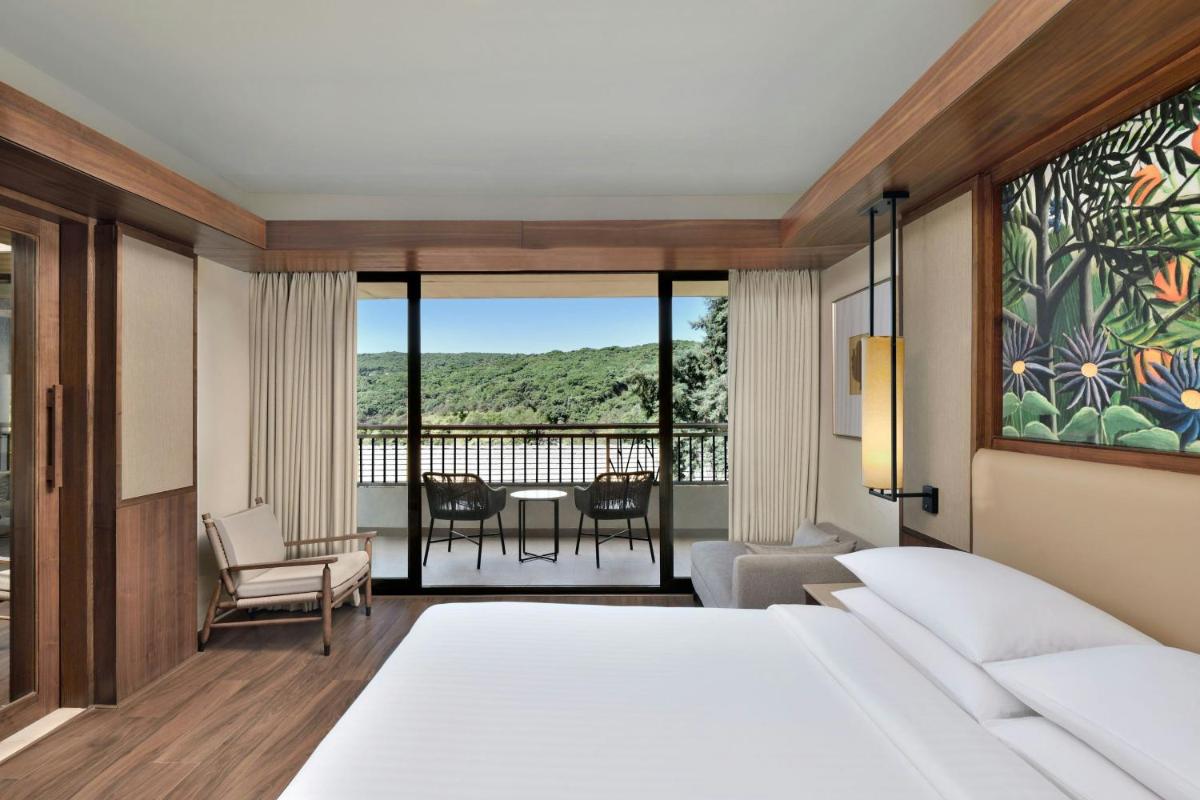 a bedroom with a bed and a view of a balcony at Courtyard by Marriott Mahabaleshwar in Mahabaleshwar