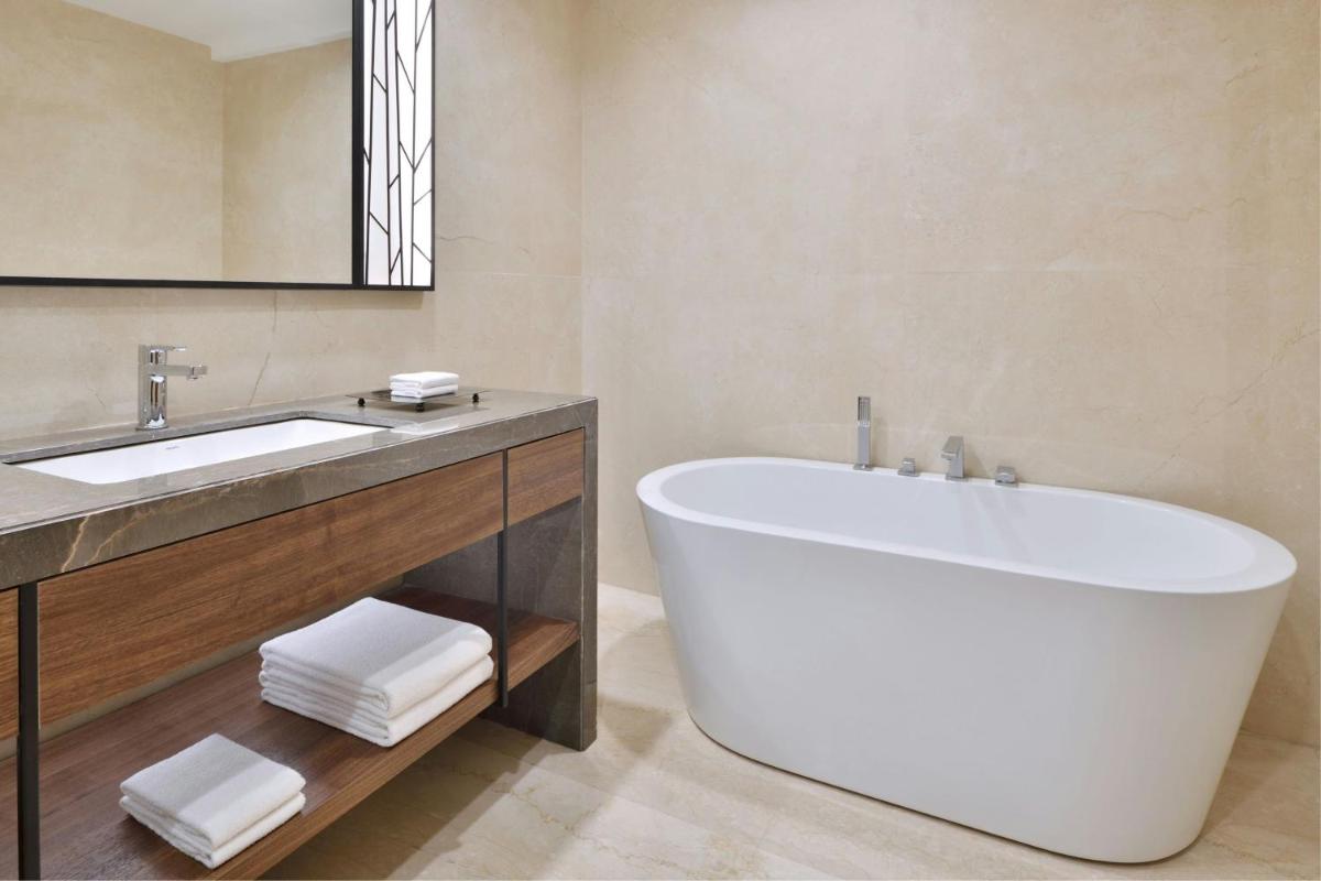a bathroom with a large tub and a sink at Courtyard by Marriott Mahabaleshwar in Mahabaleshwar