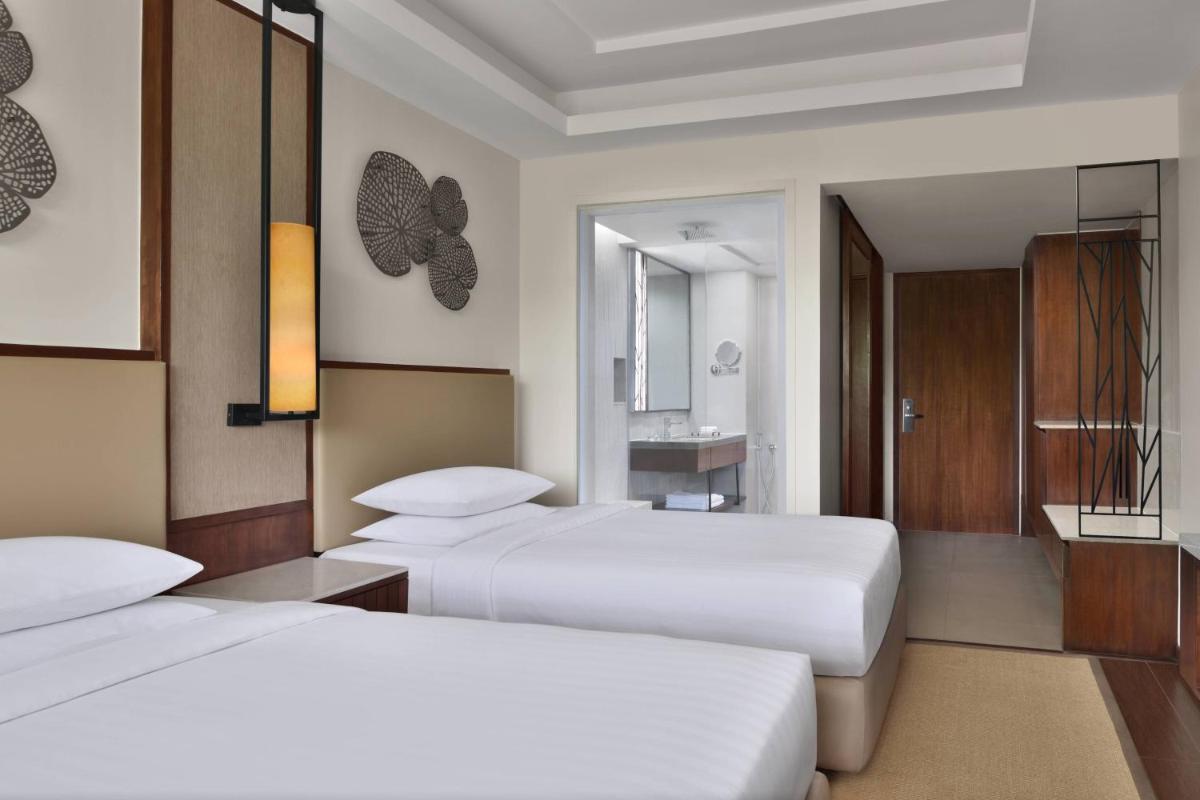 a hotel room with two beds and a bathroom at Courtyard by Marriott Mahabaleshwar in Mahabaleshwar
