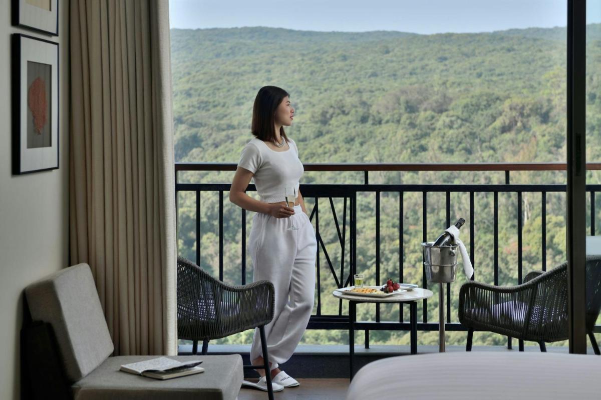 a woman standing in a hotel room looking out the window at Courtyard by Marriott Mahabaleshwar in Mahabaleshwar