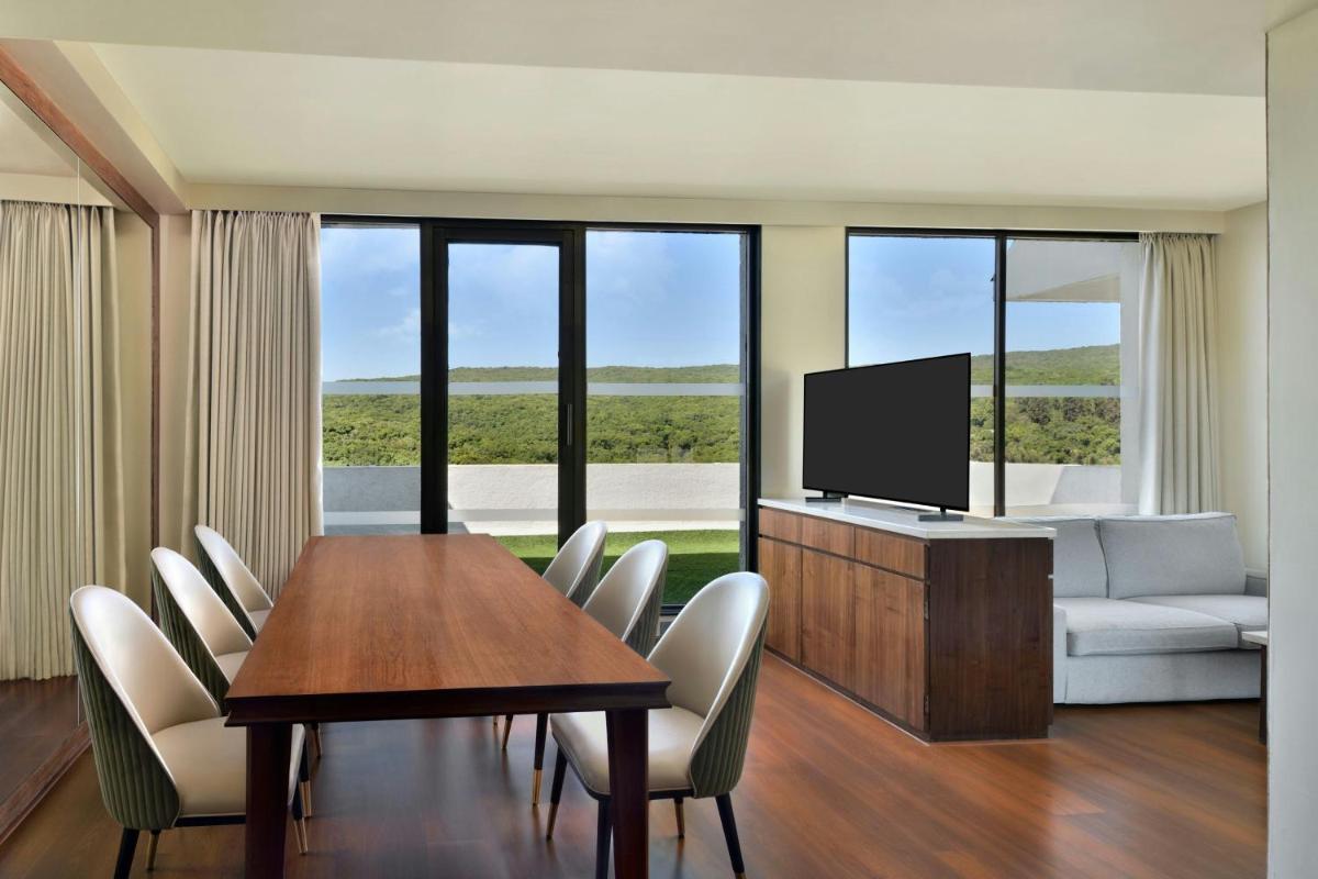 a living room with a dining table and a television at Courtyard by Marriott Mahabaleshwar in Mahabaleshwar
