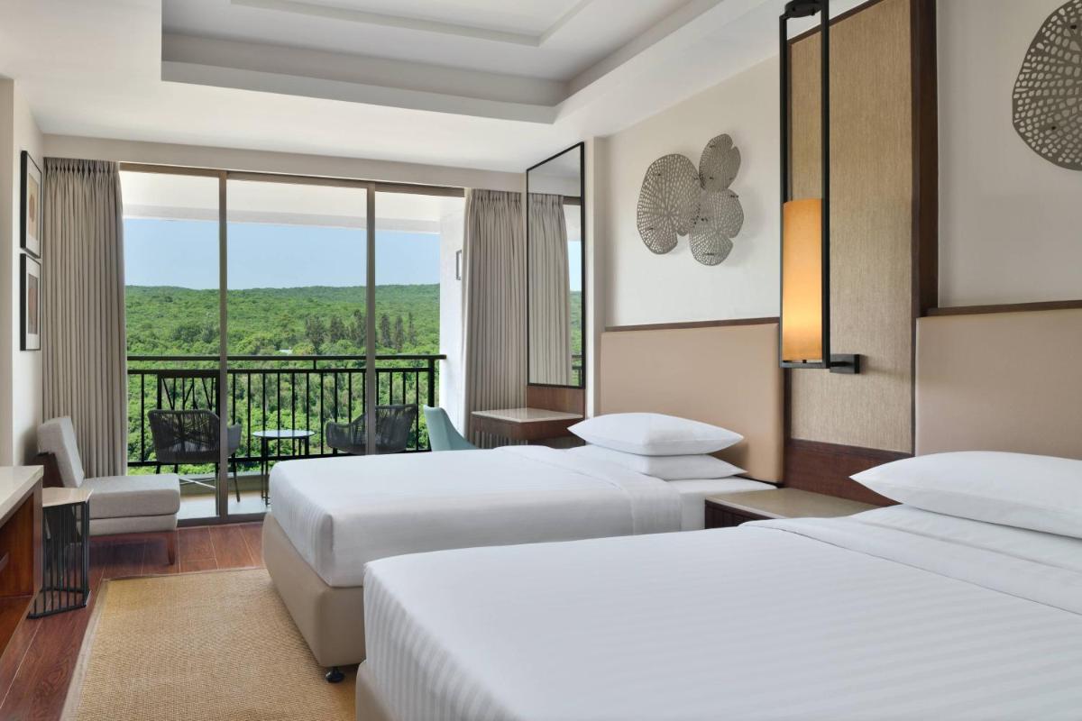a hotel room with two beds and a balcony at Courtyard by Marriott Mahabaleshwar in Mahabaleshwar