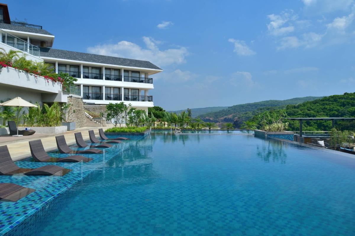 a swimming pool with lounge chairs and a hotel at Courtyard by Marriott Mahabaleshwar in Mahabaleshwar