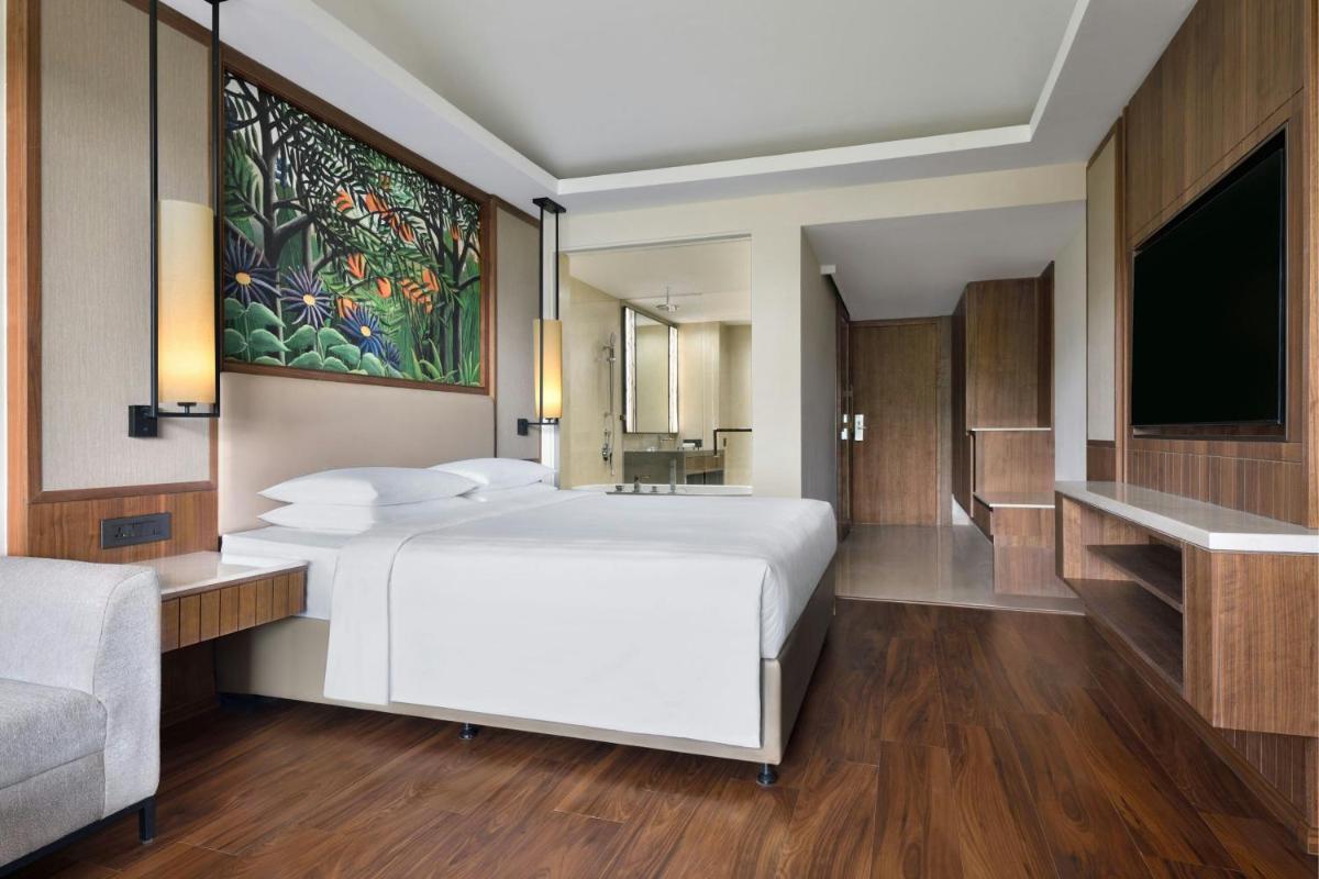 a bedroom with a large white bed and a flat screen tv at Courtyard by Marriott Mahabaleshwar in Mahabaleshwar