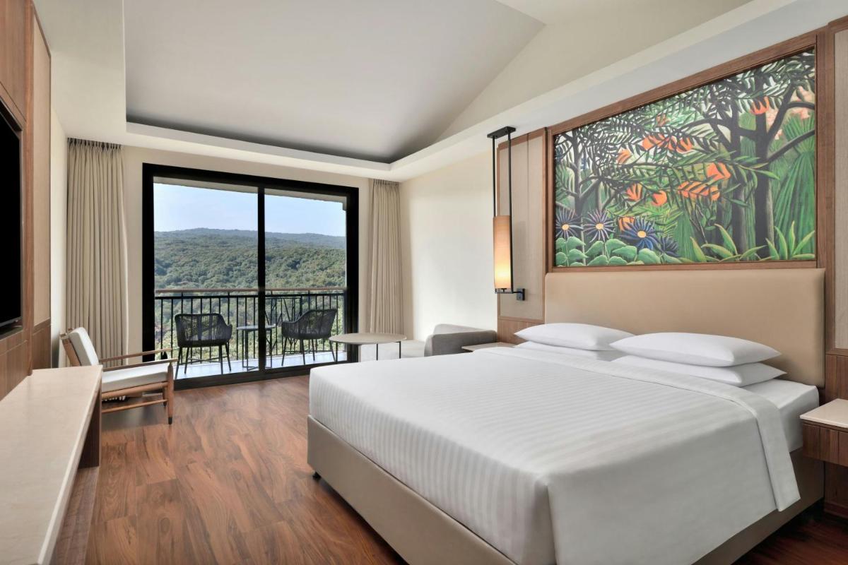 a bedroom with a large white bed and a large window at Courtyard by Marriott Mahabaleshwar in Mahabaleshwar