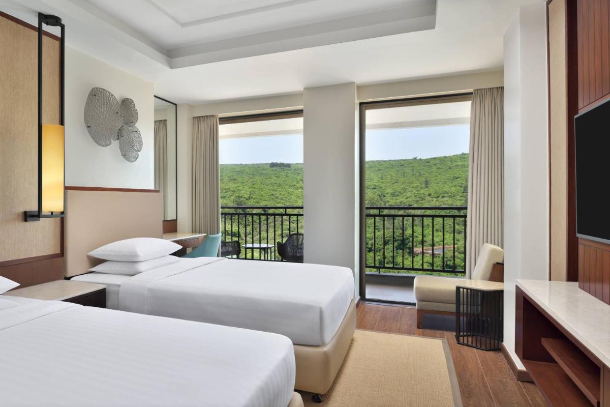 a hotel room with two beds and a balcony at Courtyard by Marriott Mahabaleshwar in Mahabaleshwar
