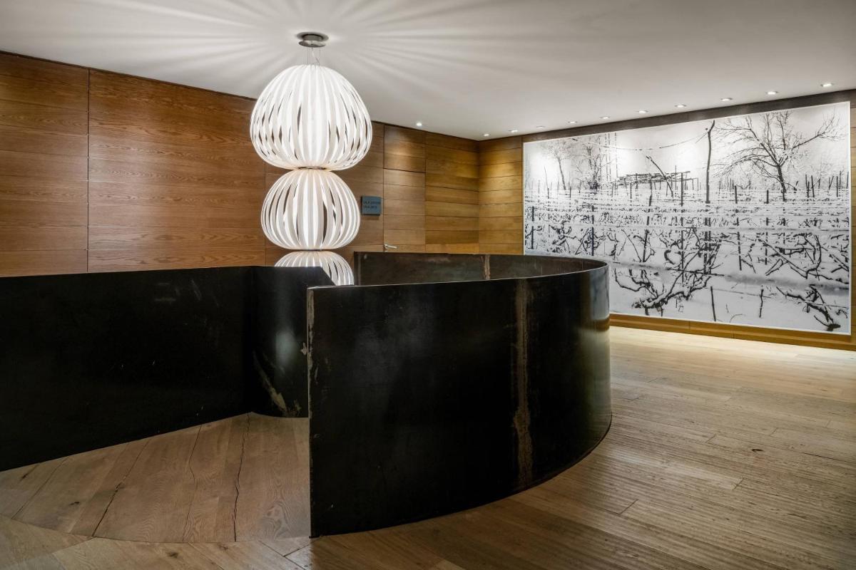 Un vestíbulo con una mesa negra y dos lámparas de araña. en Hotel AC Baqueira Ski Resort, Autograph Collection, en Baqueira Beret