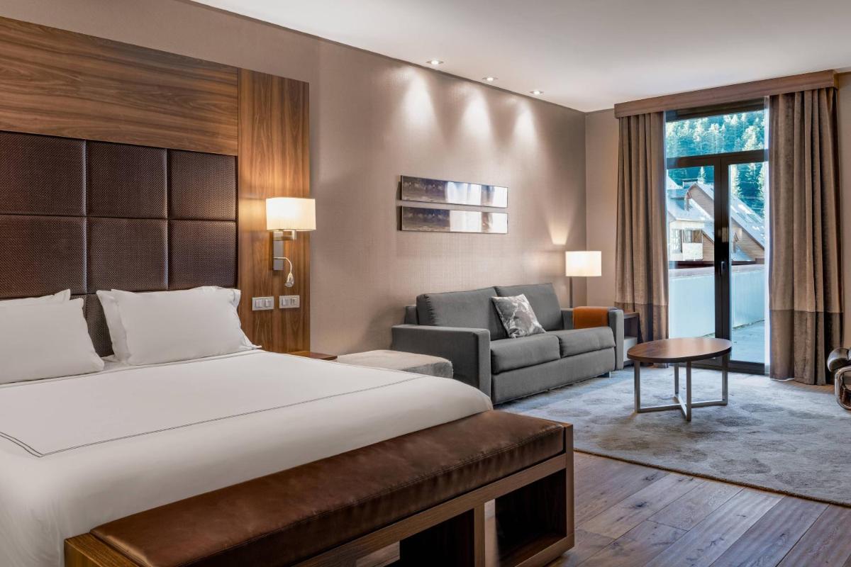 Un dormitorio con una cama y una sala de estar. en Hotel AC Baqueira Ski Resort, Autograph Collection, en Baqueira Beret