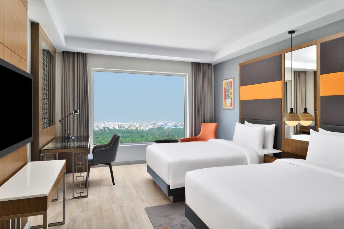 a hotel room with two beds and a window at Le Meridien Hyderabad in Hyderabad