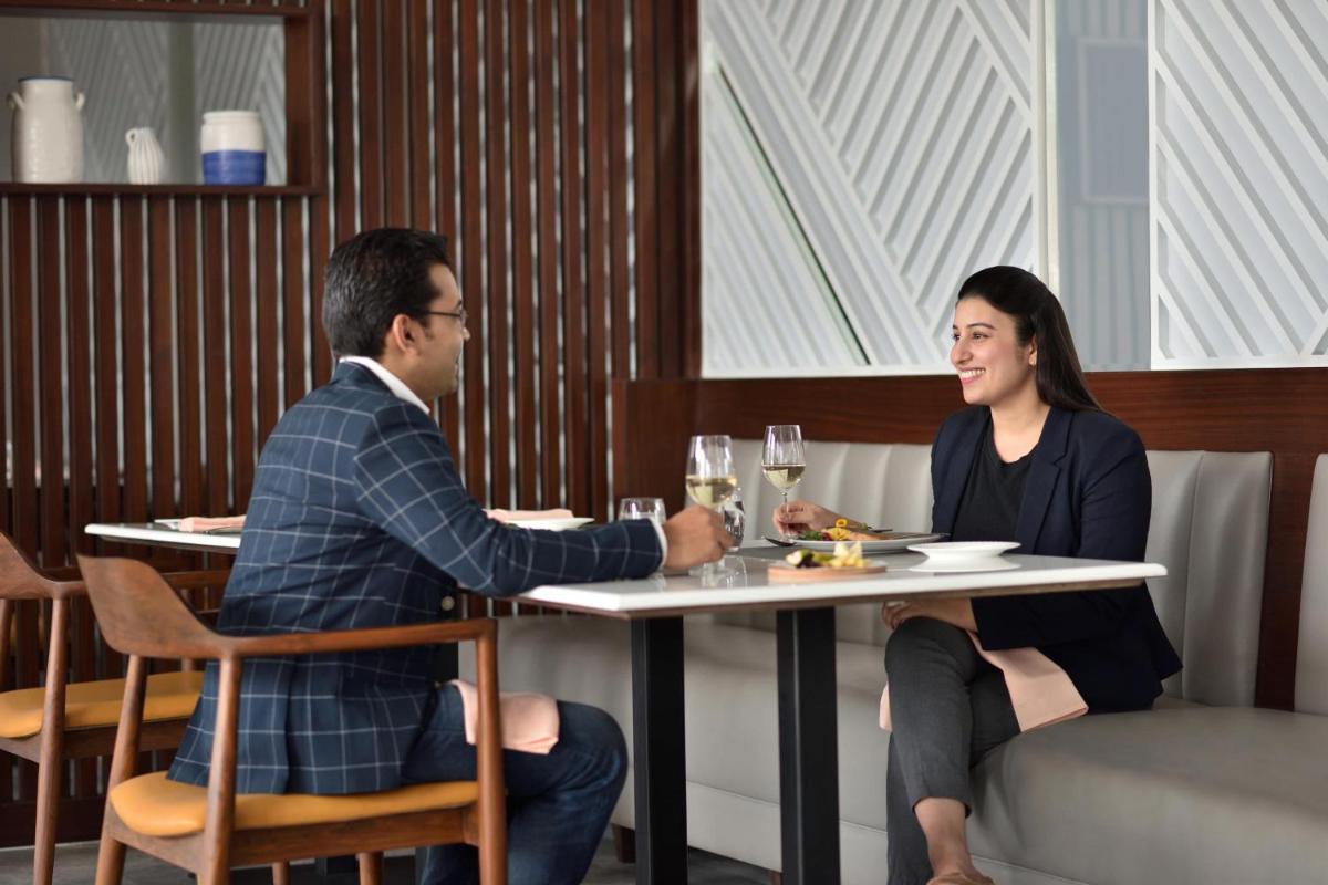 a man and a woman sitting at a table in a restaurant at Le Meridien Hyderabad in Hyderabad