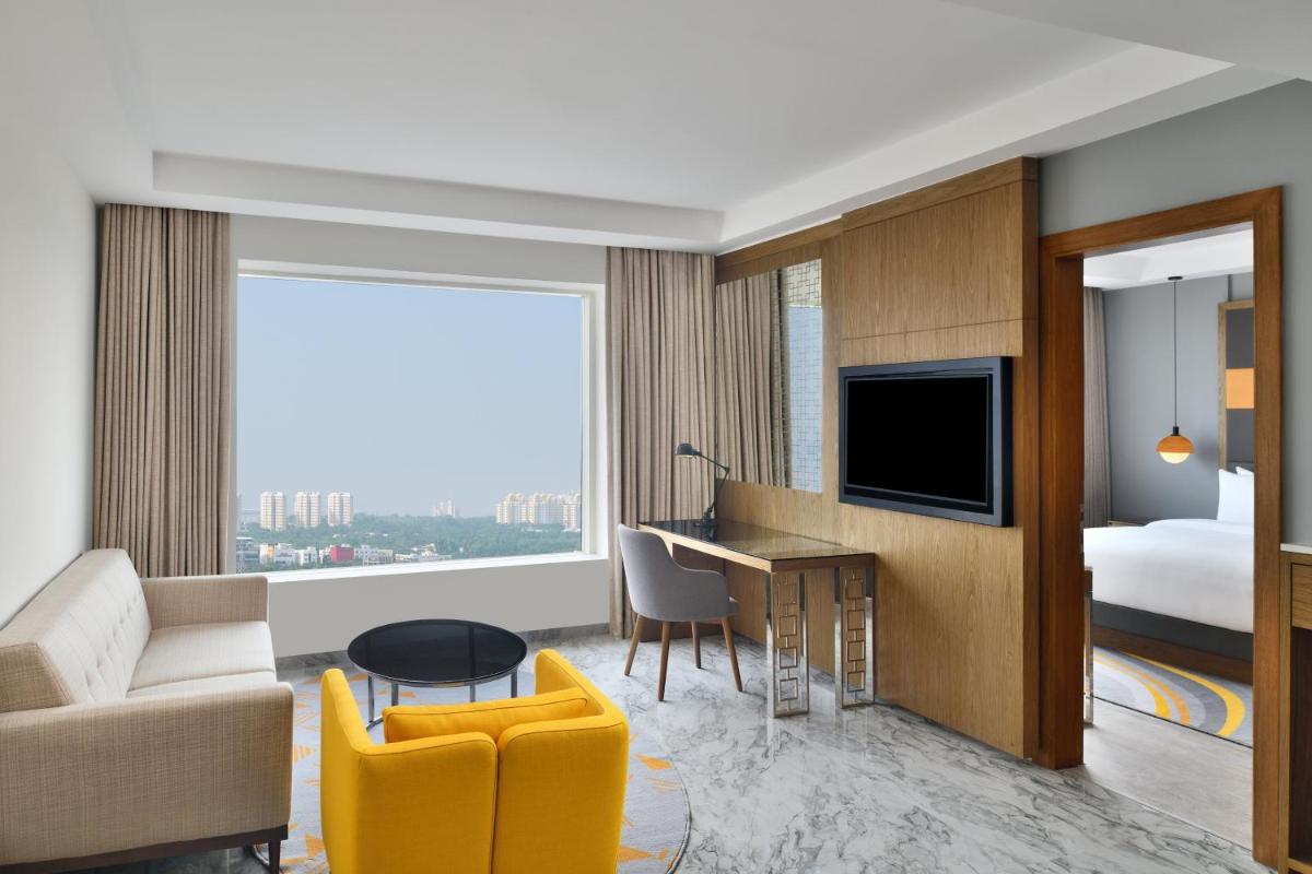a living room with a couch and a desk with a television at Le Meridien Hyderabad in Hyderabad