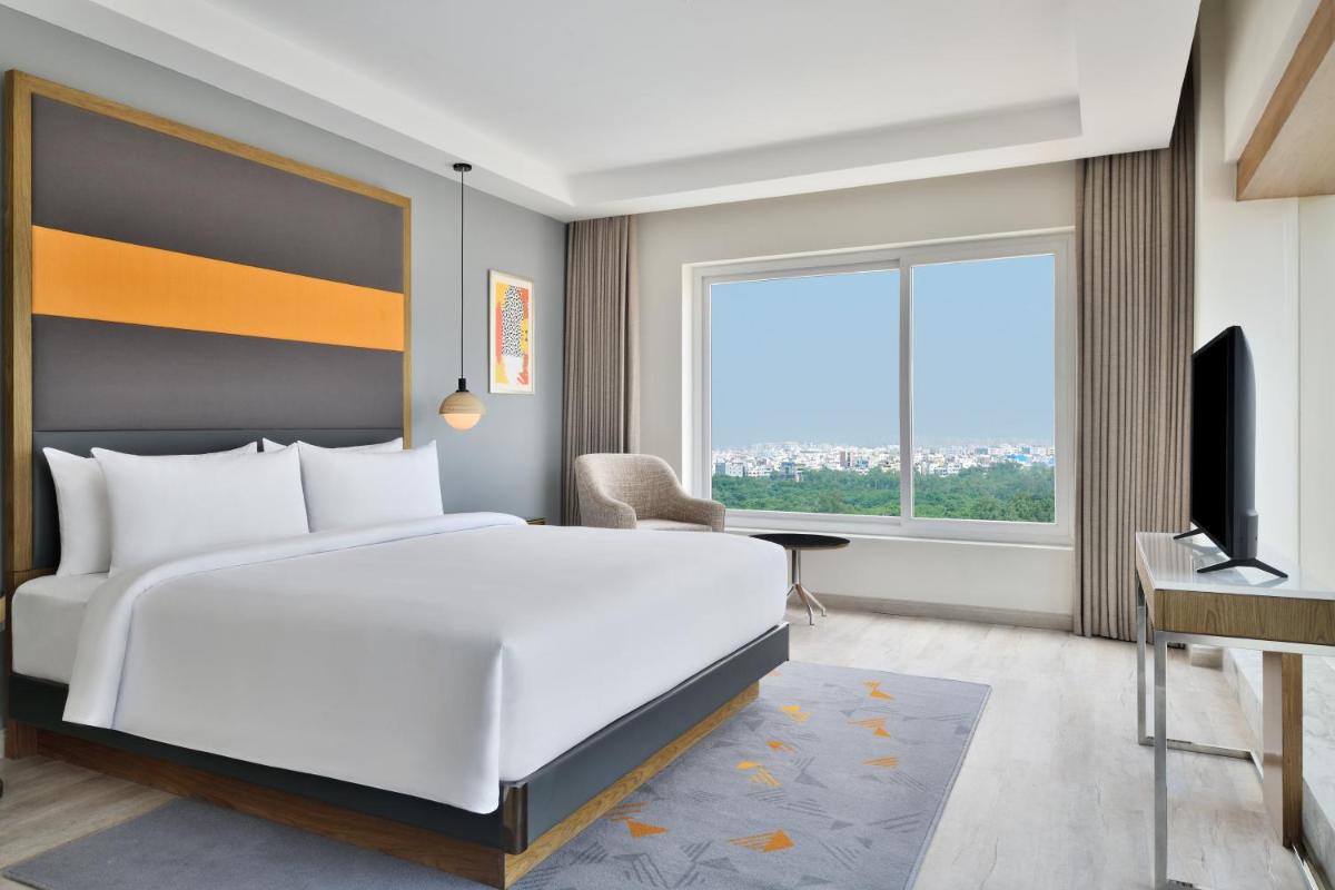 a bedroom with a large white bed and a window at Le Meridien Hyderabad in Hyderabad