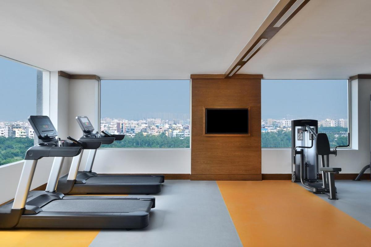 a gym with cardio equipment and a large window at Le Meridien Hyderabad in Hyderabad