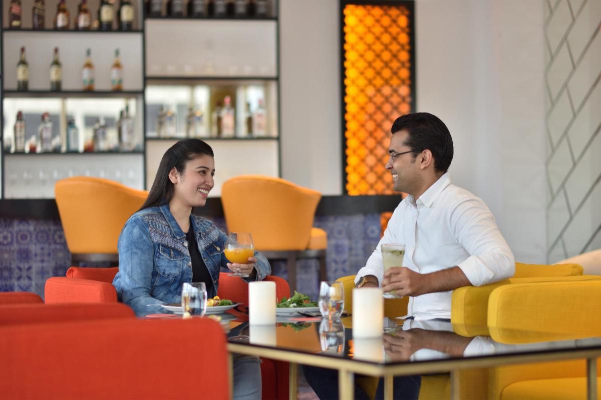 a man and woman sitting at a table in a restaurant at Le Meridien Hyderabad in Hyderabad