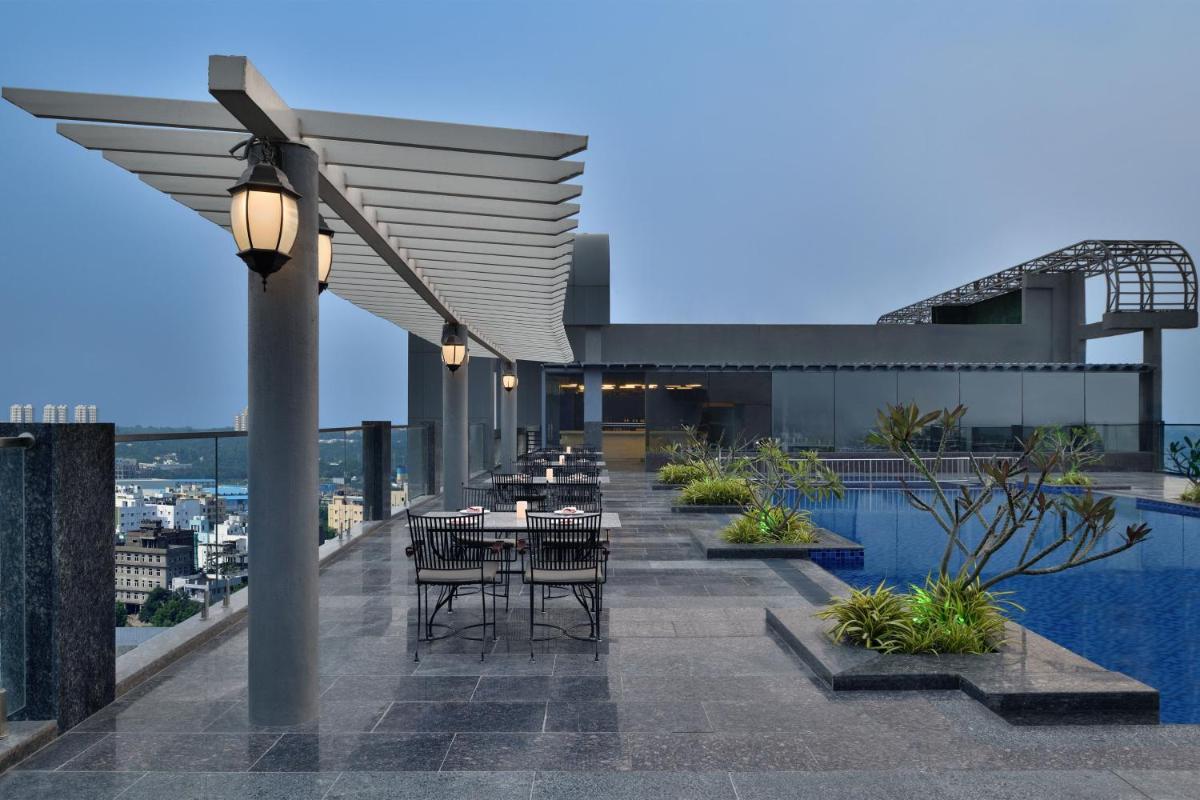a rooftop patio with tables and chairs on a building at Le Meridien Hyderabad in Hyderabad
