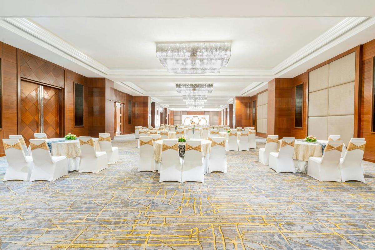 a large banquet hall with tables and white chairs at Le Meridien Hyderabad in Hyderabad