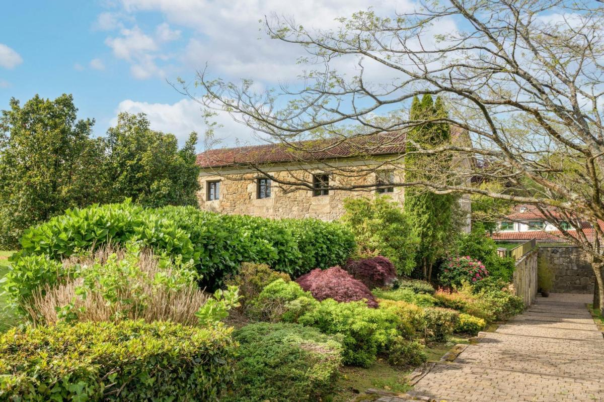 un jardín frente a una casa de piedra en Hotel Palacio del Carmen, Autograph Collection, en Santiago de Compostela