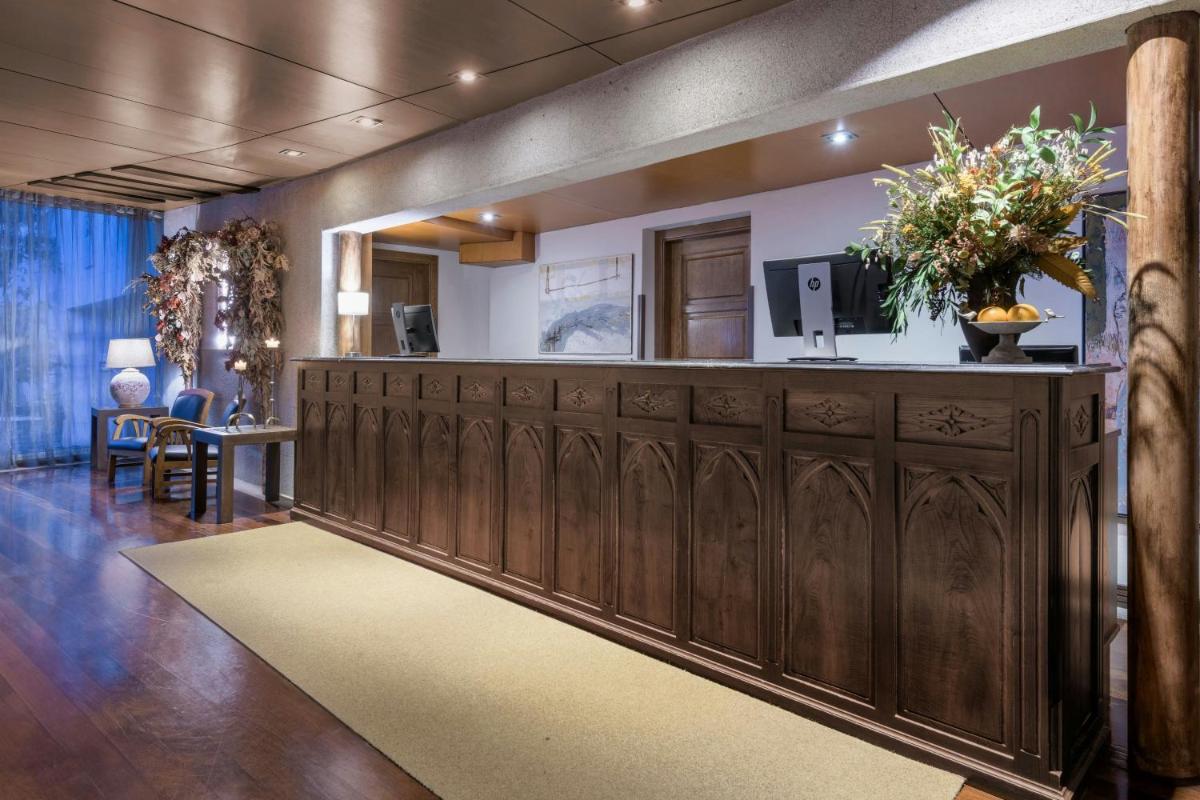 un vestíbulo con un gran armario de madera con TV. en Hotel Palacio del Carmen, Autograph Collection, en Santiago de Compostela