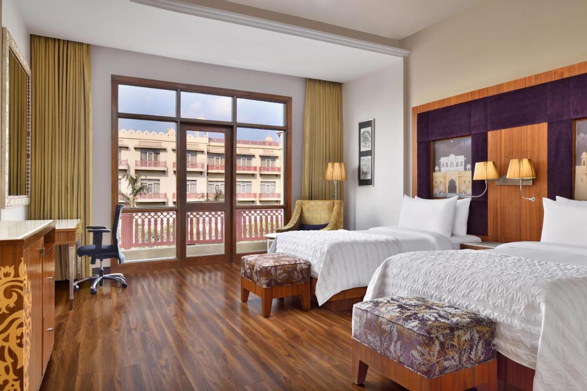 a hotel room with two beds and a balcony at Le Meridien Jaipur Resort & Spa in Jaipur