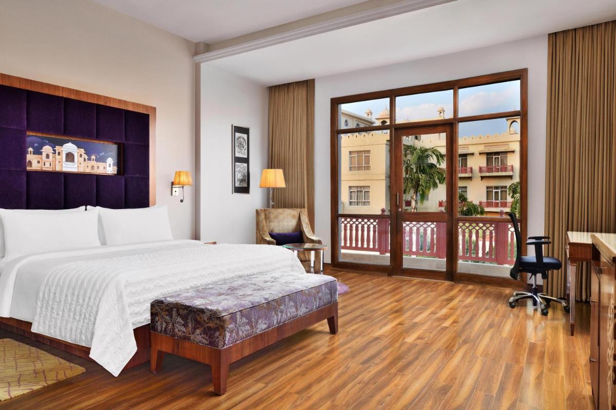 a bedroom with a large bed and a balcony at Le Meridien Jaipur Resort & Spa in Jaipur
