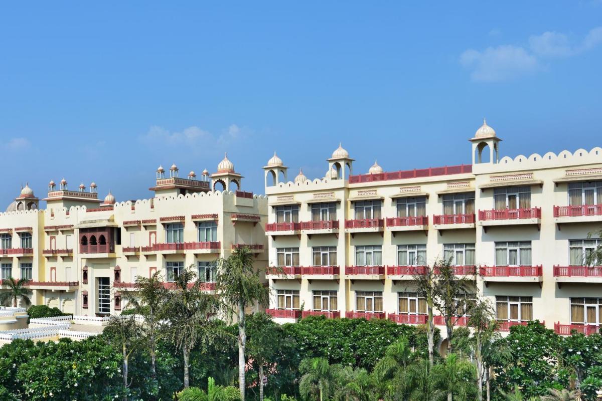 a large white building with trees in front of it at Le Meridien Jaipur Resort & Spa in Jaipur