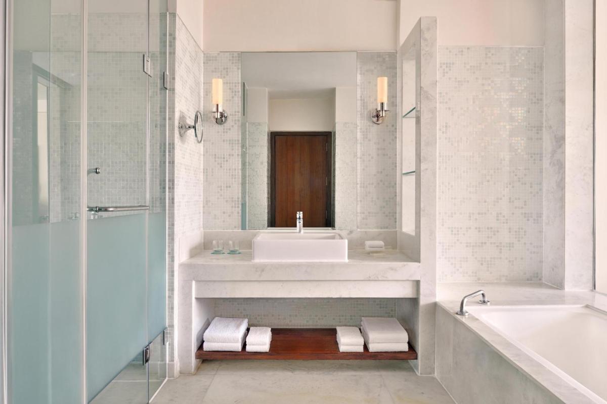 a bathroom with a sink and a tub and a mirror at Le Meridien Jaipur Resort & Spa in Jaipur