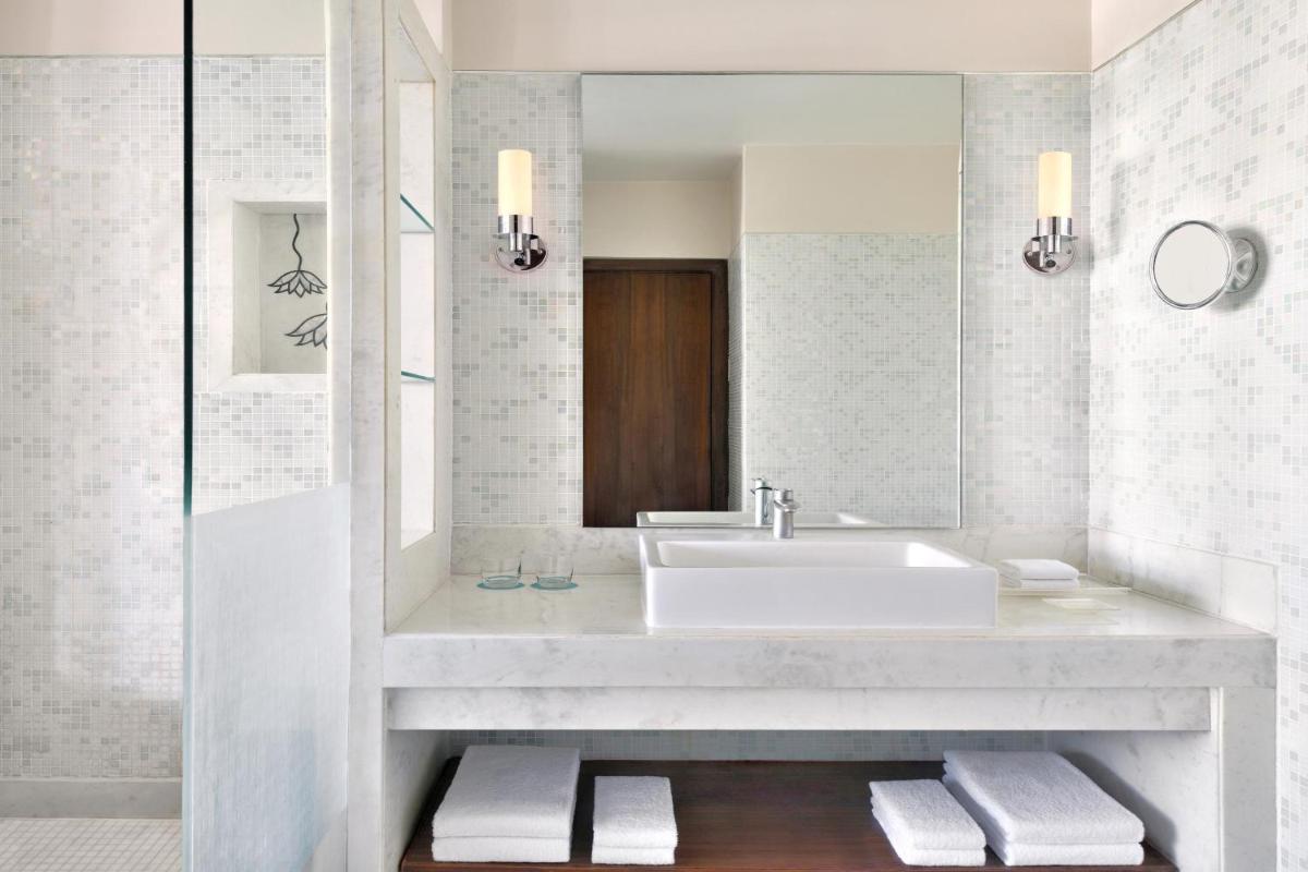 a white bathroom with a sink and a mirror at Le Meridien Jaipur Resort & Spa in Jaipur