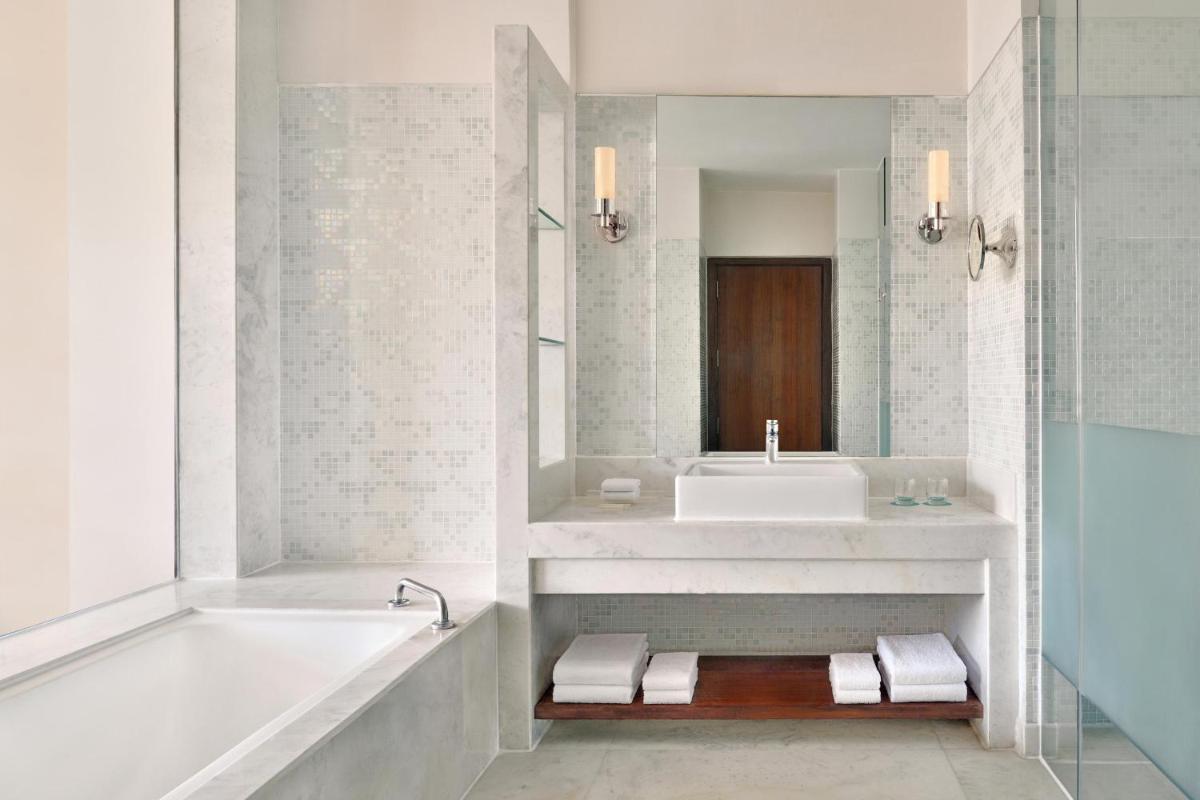 a white bathroom with a tub and a sink at Le Meridien Jaipur Resort & Spa in Jaipur