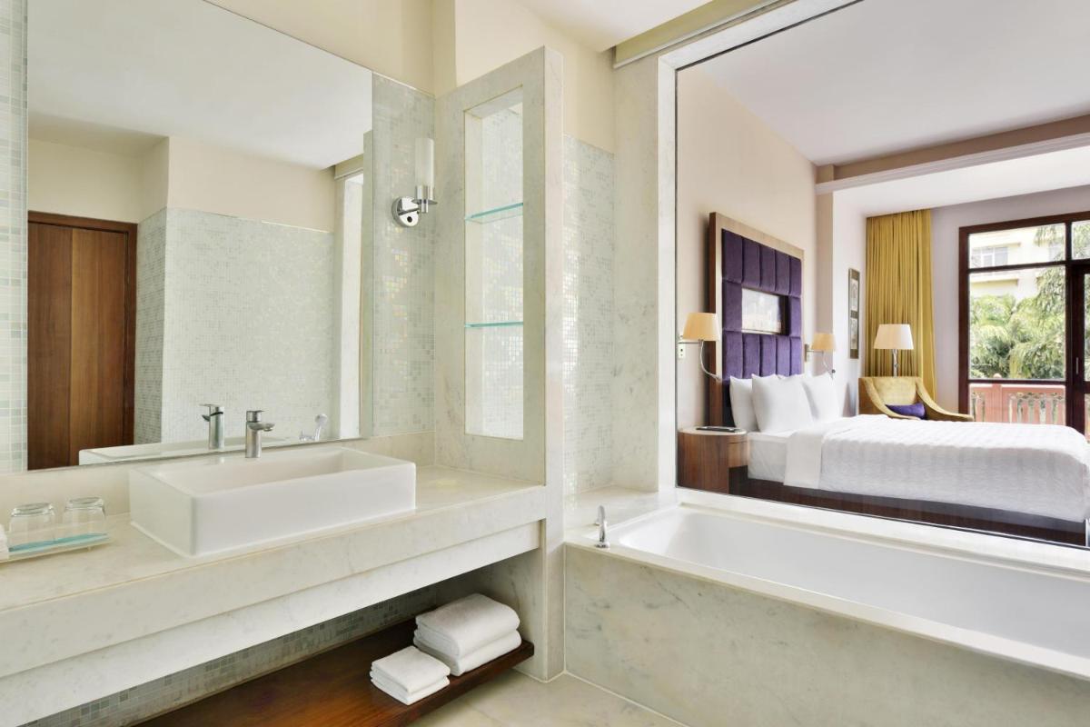 a bathroom with a tub and a sink and a bed at Le Meridien Jaipur Resort & Spa in Jaipur