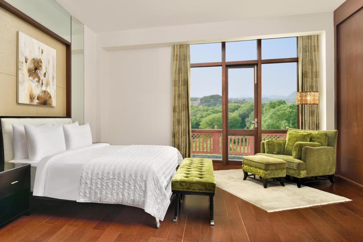 a bedroom with a bed and a large window at Le Meridien Jaipur Resort & Spa in Jaipur