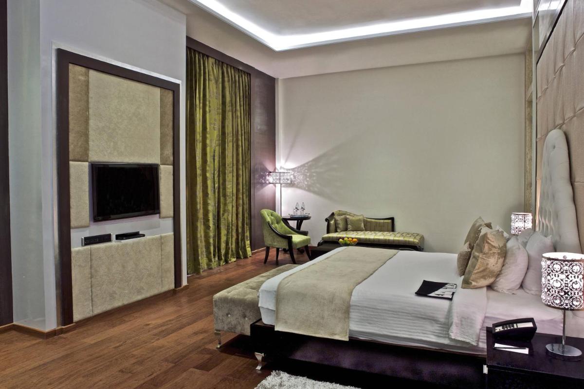 a bedroom with a large bed and a television at Le Meridien Jaipur Resort & Spa in Jaipur