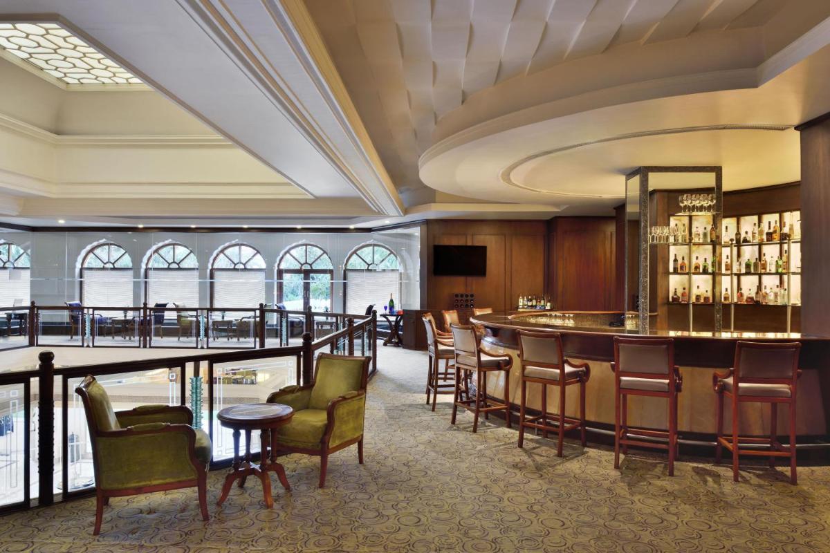 a bar in a hotel lobby with chairs and tables at Le Meridien Jaipur Resort & Spa in Jaipur