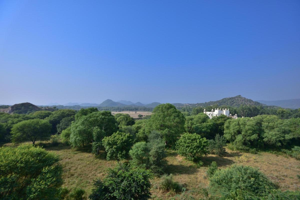 a house in the middle of a forest of trees at Le Meridien Jaipur Resort & Spa in Jaipur