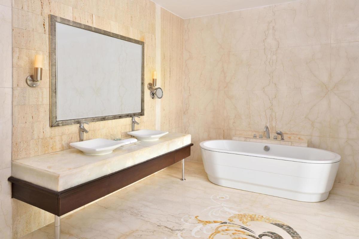 a bathroom with a tub and a sink and a mirror at Le Meridien Jaipur Resort & Spa in Jaipur