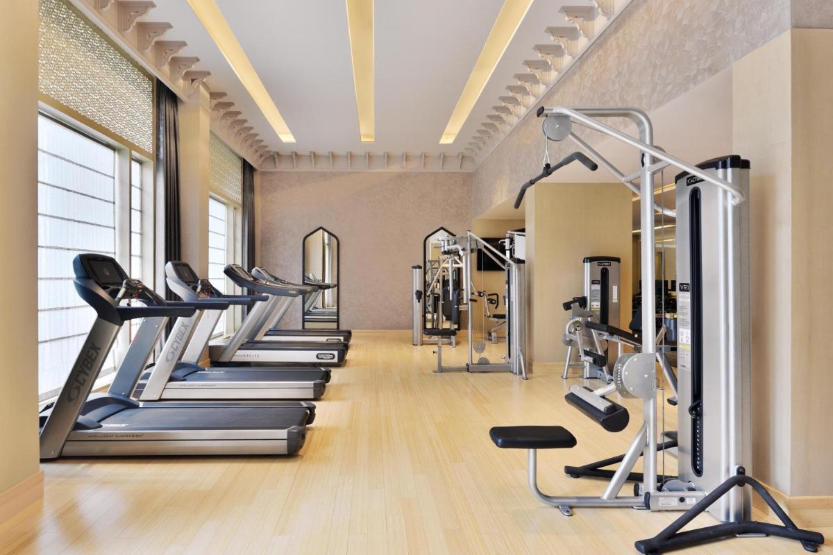 a gym with treadmills and elliptical machines at Le Meridien Jaipur Resort & Spa in Jaipur