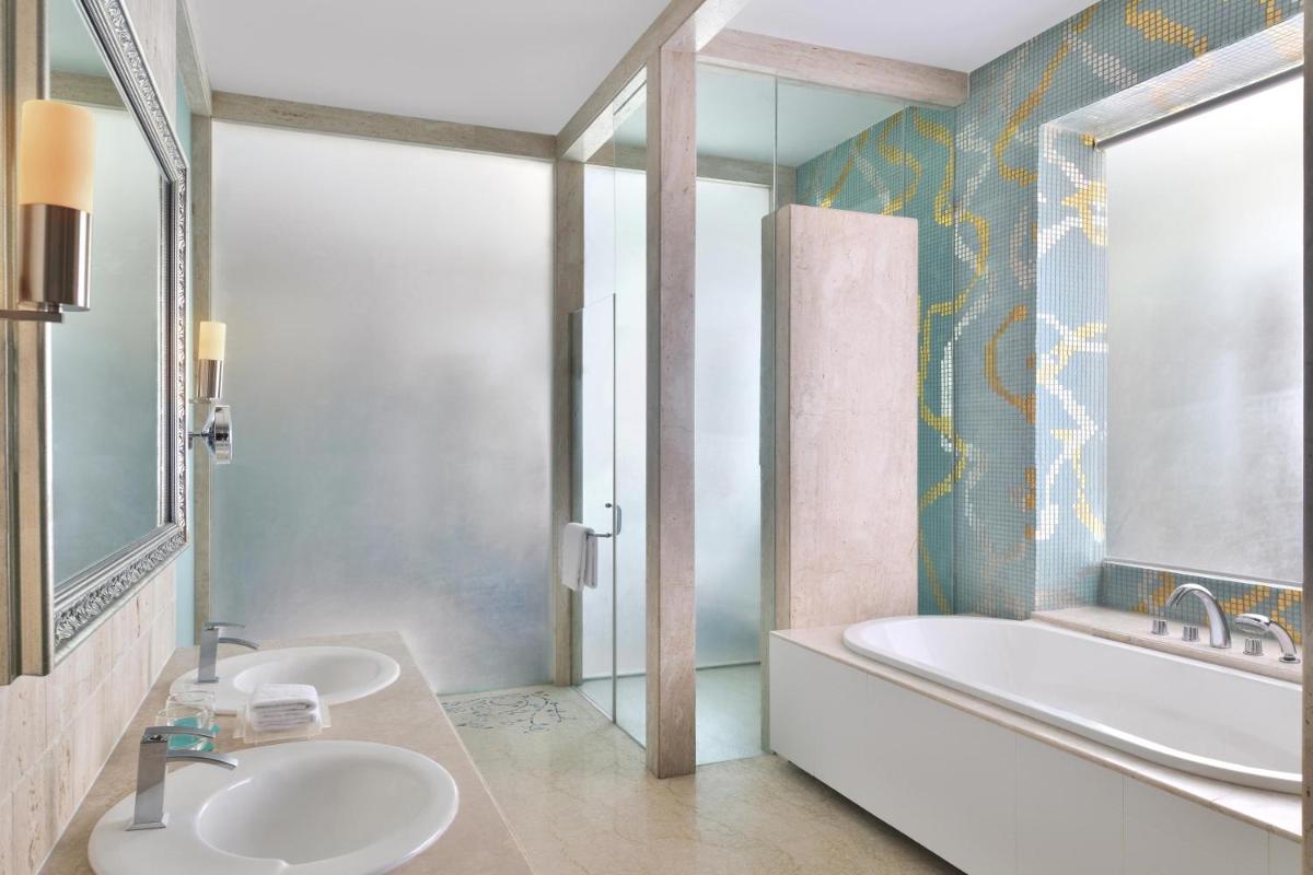a bathroom with two sinks and a tub and a mirror at Le Meridien Jaipur Resort & Spa in Jaipur