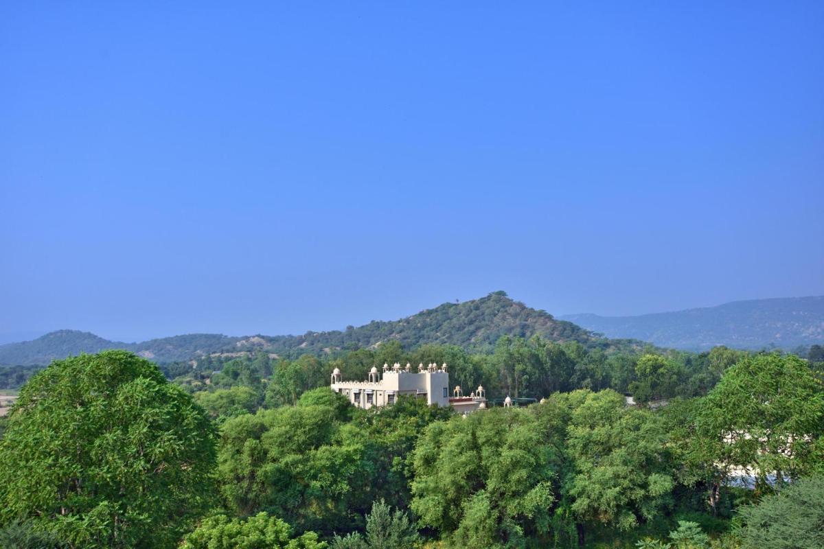 a large white house in the middle of trees at Le Meridien Jaipur Resort & Spa in Jaipur